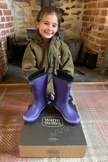 girl unpacks purple warm wellies